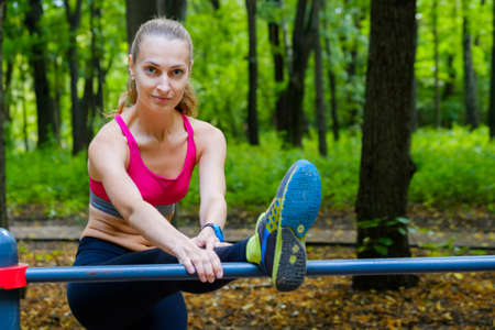 Young slim woman stretching in a training ground in a park