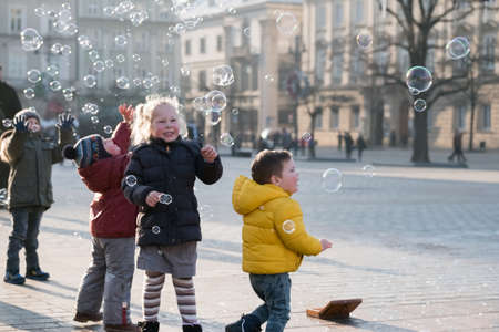 Krakow, Poland - December 20, 2016: Children age 4-5 years playing with soap bubbles on the square at day timeのeditorial素材