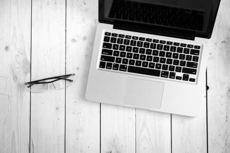 Laptop and glasses on wooden desk, top viewの写真素材