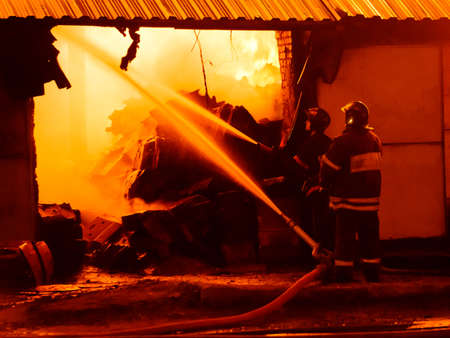 Firefighters extinguish a fire in a burning warehouseの写真素材