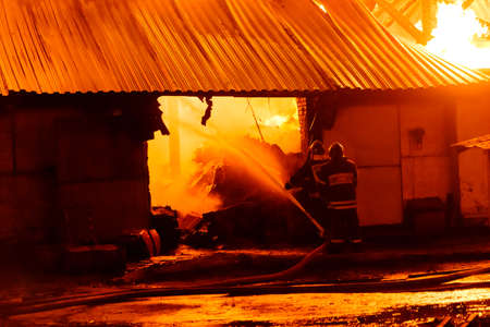 Firefighters extinguish a fire in a burning warehouseの写真素材