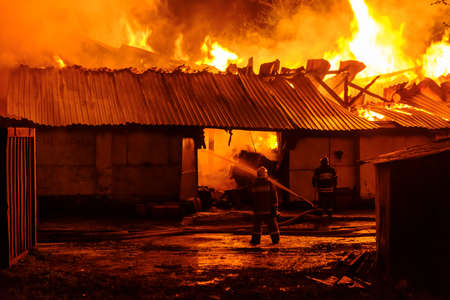 Firefighters extinguish a fire in a burning warehouseの写真素材