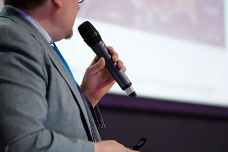 Businessman talking at conference holding a microphoneの写真素材