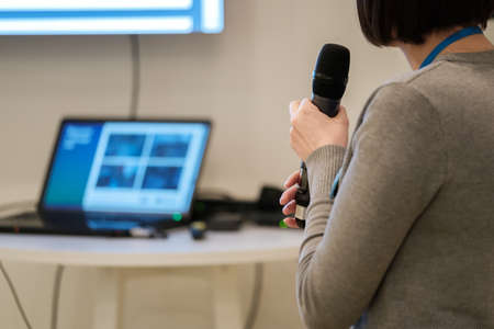 Businesswoman talking at conference holding a microphone