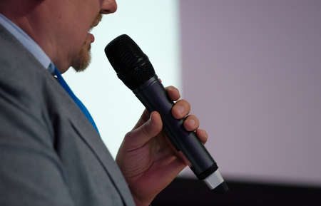 Businessman talking at conference holding a microphoneの写真素材