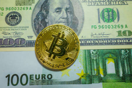 Golden bitcoin coin on the one hundred dollars and euro banknotes. Macro. Cryptocurrency conceptの写真素材