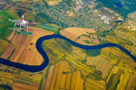 Quadrocopter flying over farmland at fall