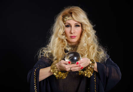 Woman fortune teller with crystal ball portrait on blackの写真素材