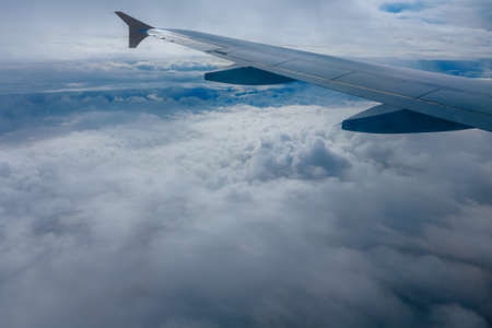 Wing of flying airplane in the clouds