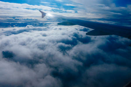 Wing of flying airplane in the clouds