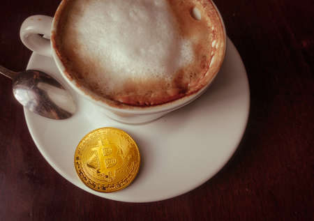 Capuccino and bitcoin gold coin on the table in cafe top view Payment by crypto currency conceptの写真素材