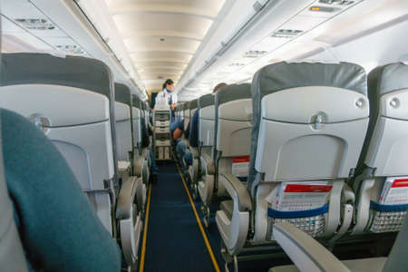 Stewardess offers food and drinks to economy class passengers on the planeの写真素材