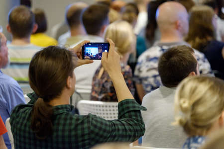 Man takes a picture of the presentation at the conference hall using smartphoneの写真素材