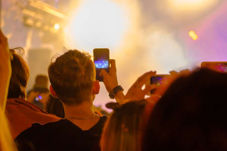 Concert visitor shoots video on a smartphoneの写真素材