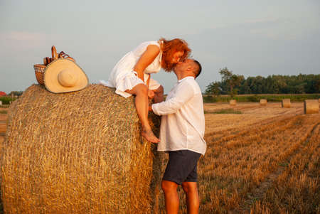 Romantic rendezvous on a freshly cut field near a haystackの写真素材