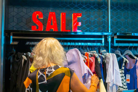 Woman choosing clothes in a clothing shop during the sale