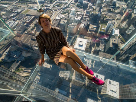 Tourists posing on a glass floor in a skyscraperの写真素材