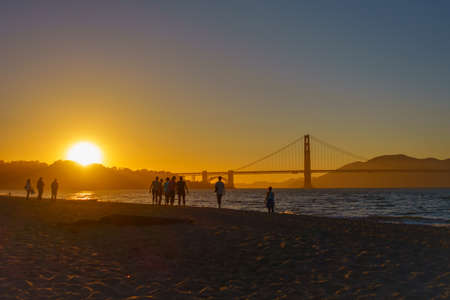 Bridge Golden Gate at San Francisco sunset time landscape, peope walking on a beach