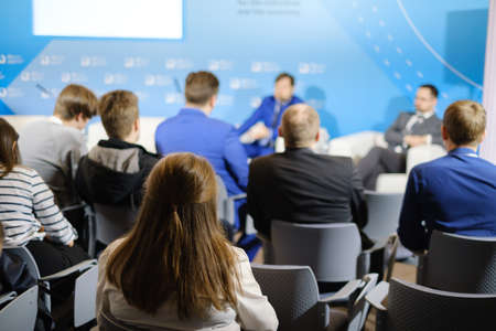 Business conference participants listen to lecturer in hall