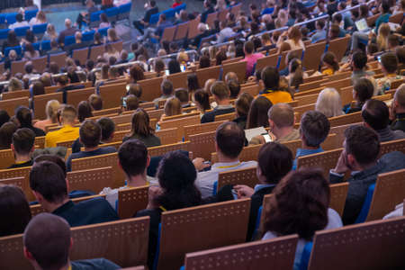 Business conference attendees sit and listen to lecturer, rear viewの写真素材