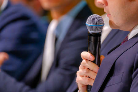 Man speaks, holding a microphone in his hand