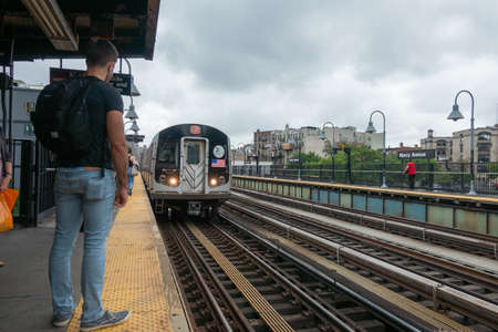 New York, USA - September 6, 2018: Back view of male passenger standing on platform of railway station and waiting for arriving subway train in New York cityのeditorial素材