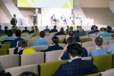 Business conference attendees sit and listen to lecturer at modern hall, rear viewの写真素材