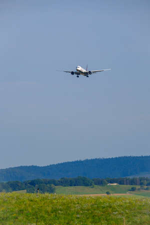 Zurich, Switzerland - July 19, 2018: From below of big white plane Air Canada airlines company flying low above green field with blue sky on backgroundのeditorial素材