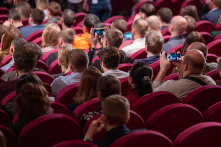 Business conference attendees sit and listen to lecturer, rear viewの写真素材