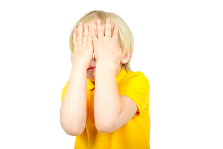Boy child closes his eyes with hands isolated on white backgroundの写真素材