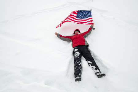 One man hold US flag lies in snowの写真素材