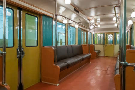 Illuminated interior of vintage train with soft benches on station in subway in city