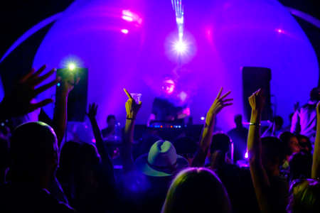 Energetic crowd of people and professional DJs dancing during music festival at open air partyの写真素材