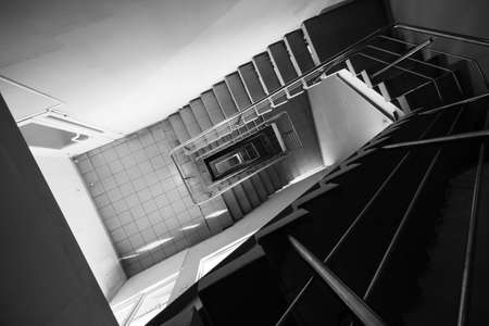 Black and white tiled stairway with metal railing leading down inside contemporary building