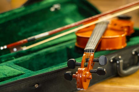 Closeup bow placed on strings of classic violin in box before music concertの写真素材