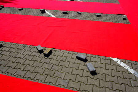 Abstract geometric texture and background with gray stone pavement covered with bright red rubber stripesの写真素材