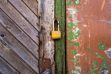 Closeup of small lock hanging on aged wooden door in weathered plaster wallの写真素材
