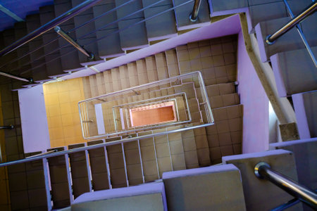 Top view of tiled stairway with metal railing leading down inside contemporary buildingの写真素材