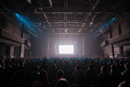 Audience sitting in front of stage with screen