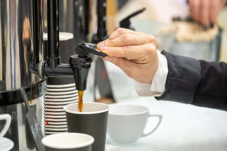 Businessperson pouring coffee into cup