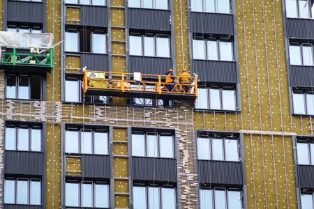 Workers on suspended scaffolding outside buildingの写真素材