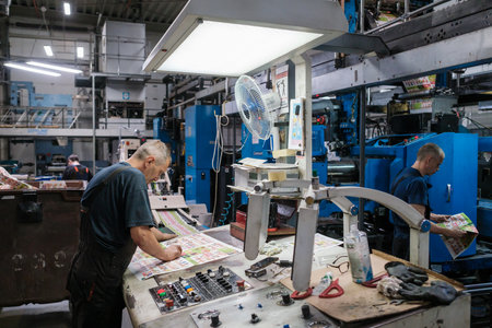 Male worker controlling printing machineのeditorial素材