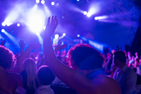 Curly haired man with hand up at concertの写真素材