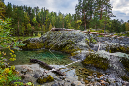 Huge rocks at riverbank with autumn trees in background at Altai, Russiaの写真素材