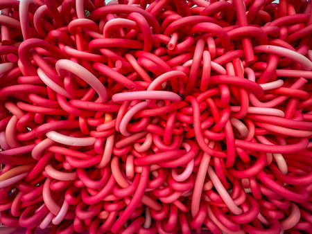 Close-up of a vibrant tangle of red rubber tubes creating an abstract texture.の写真素材