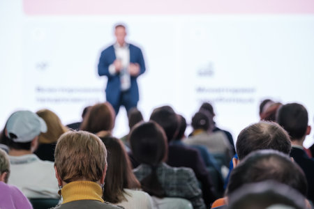 Rear view of audience watching a blurred presenter at a professional business conference seminar.の写真素材