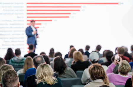 Blurred speaker engaging audience during a conference presentation in a modern venue.の写真素材