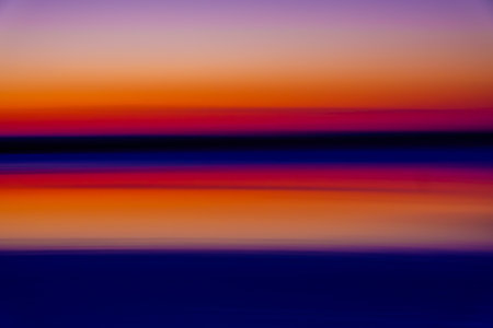A stunning abstract image of a sunset over the sea with vibrant orange, purple, and blue hues creating a serene and peaceful atmosphere.の写真素材