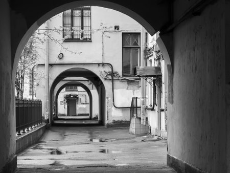Monochromatic image showcasing an old urban alleyway with archways and a gritty, nostalgic atmosphere.の写真素材