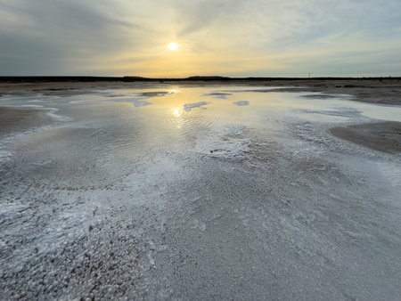 A stunning sunset reflected on salt flats creating a tranquil and serene scene, evoking calm and...